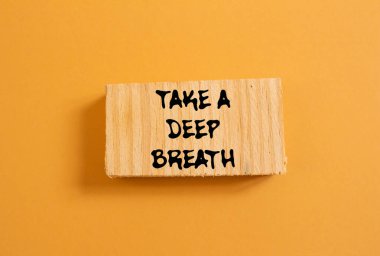 Turuncu arka planda tahta parçasına yazılmış derin bir nefes mesajı alın. Kavramsal bir nefes alma sembolü. Boşluğu kopyala.