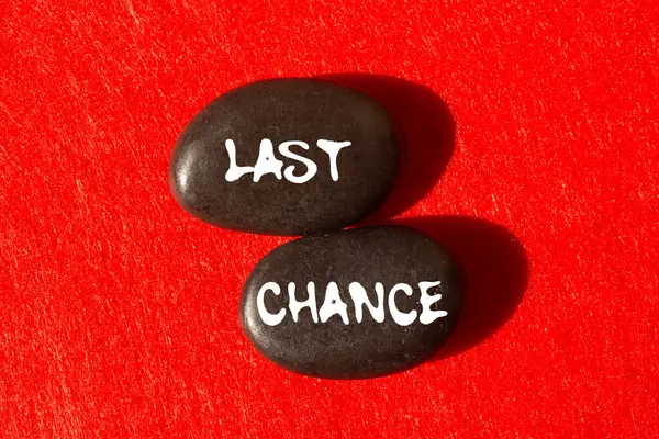 Kırmızı arka planda siyah taşlara yazılmış son şans mesajı. Kavramsal son şans sembolü. Boşluğu kopyala.