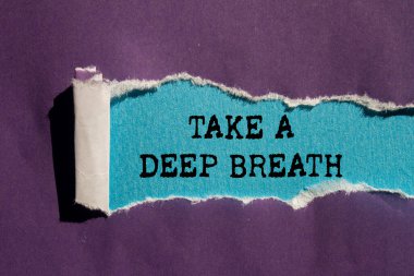 Mavi arka plandaki yırtık mor kağıda yazılmış derin bir nefes mesajı alın. Kavramsal bir nefes alma sembolü. Boşluğu kopyala.