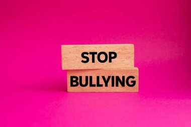 Ahşap bloklara pembe arka planda yazılmış mesajlara zorbalık etmeyi bırak. Kavramsal zorbalık sembolünü durdur. Boşluğu kopyala.