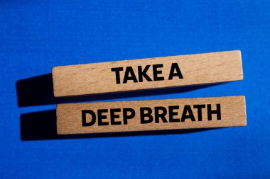 Mavi arka plandaki tahta bloklara yazılmış derin bir nefes mesajı alın. Kavramsal bir nefes alma sembolü. Boşluğu kopyala.