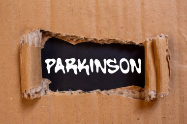 Siyah arka planda yırtık karton kağıda Parkinson mesajı yazılmış. Kavramsal Parkinson sembolü. Boşluğu kopyala.