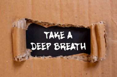 Siyah arka planda yırtılmış karton kağıda yazılmış derin bir nefes mesajı alın. Kavramsal bir nefes alma sembolü. Boşluğu kopyala.