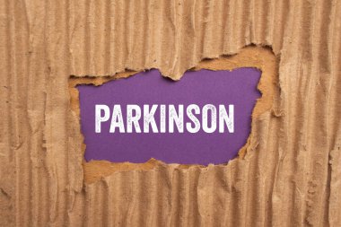 Mor arka planda yırtık karton kağıda Parkinson mesajı yazılmış. Kavramsal Parkinson sembolü. Boşluğu kopyala.