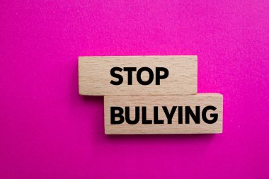 Ahşap bloklara pembe arka planda yazılmış mesajlara zorbalık etmeyi bırak. Kavramsal zorbalık sembolünü durdur. Boşluğu kopyala.