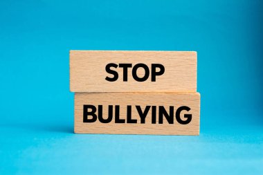 Mavi arka plandaki tahta bloklara yazılan mesajlara zorbalık etmeyi bırak. Kavramsal zorbalık sembolünü durdur. Boşluğu kopyala.