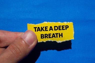 Mavi arka planda yırtık sarı kağıt parçasına yazılmış derin bir nefes mesajı alın. Kavramsal bir nefes alma sembolü. Boşluğu kopyala.