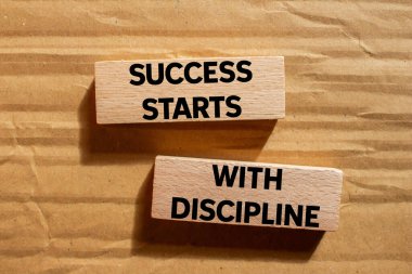 Başarı, karton arka plandaki tahta bloklara yazılmış disiplin mesajıyla başlar. Kavramsal başarı disiplin sembolüyle başlar. Boşluğu kopyala.