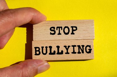 Sarı arka planda tahta bloklara yazılmış mesajlara zorbalık etmeyi bırak. Kavramsal zorbalık sembolünü durdur. Boşluğu kopyala.