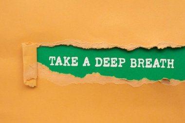 Yeşil arka planda yırtık turuncu kağıda yazılmış derin bir nefes mesajı alın. Kavramsal bir nefes alma sembolü. Boşluğu kopyala.