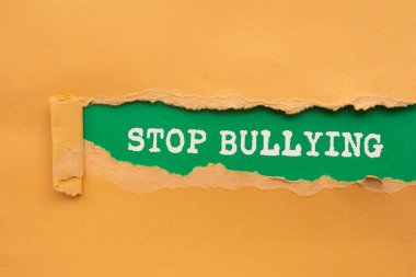 Yeşil arka planda yırtık turuncu kağıda yazılan mesajlarla uğraşmayı bırak. Kavramsal zorbalık sembolünü durdur. Boşluğu kopyala.