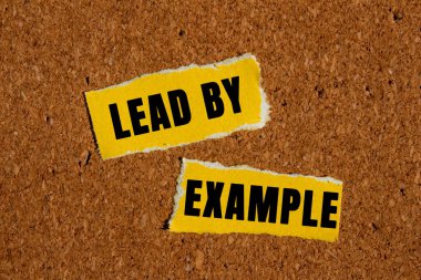 Kahverengi arkaplandaki yırtık sarı kağıt parçalarına yazılmış örnek bir mesajla. Örnek sembolle kavramsal liderlik. Boşluğu kopyala.