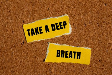 Kahverengi arka planda yırtık sarı kağıt parçalarına yazılmış derin bir nefes mesajı alın. Kavramsal bir nefes alma sembolü. Boşluğu kopyala.