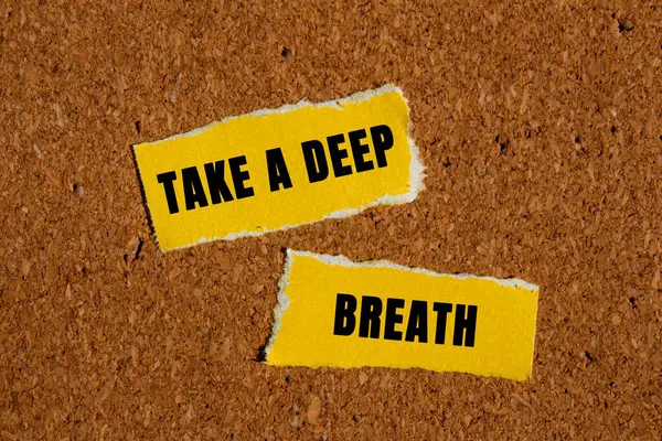 Kahverengi arka planda yırtık sarı kağıt parçalarına yazılmış derin bir nefes mesajı alın. Kavramsal bir nefes alma sembolü. Boşluğu kopyala.