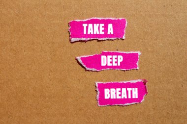 Karton arka planda yırtık pembe kağıt parçalarına yazılmış derin bir nefes mesajı alın. Kavramsal bir nefes alma sembolü. Boşluğu kopyala.