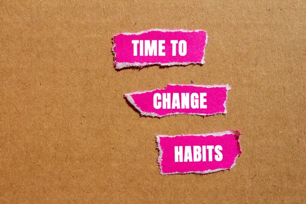 Karton arka planda yırtık pembe kağıt parçalarına yazılmış alışkanlık mesajlarını değiştirme zamanı. Alışkanlık sembolünü değiştirmek için kavramsal zaman. Boşluğu kopyala.