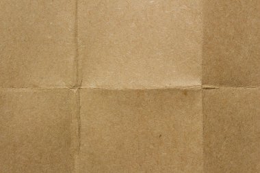 Brown kraft paper texture with fold lines. Detailed cardboard surface showing intersecting creases and natural fiber patterns.