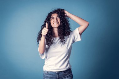 Mutlu, kendine güvenen, dişlek gülümseyen, sıradan, katı beyaz tişört giyen, güzel duygular ifade eden, güzel bir gün geçiren, baş parmağını kaldırma sembolü yapan bir kadın. İfadeler