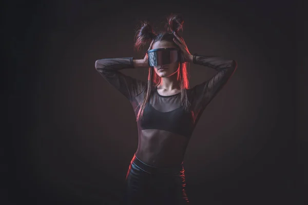 stock image Portrait of beautiful cyber model woman posing wearing futuristic glasses on head with neon light in a virtual tech environment