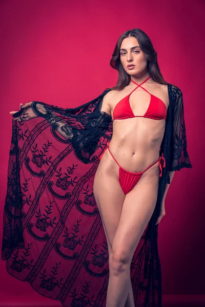 赤い背景の赤い水着を着用している美しい茶色の髪モデルのスタジオ写真撮影 — ストック写真