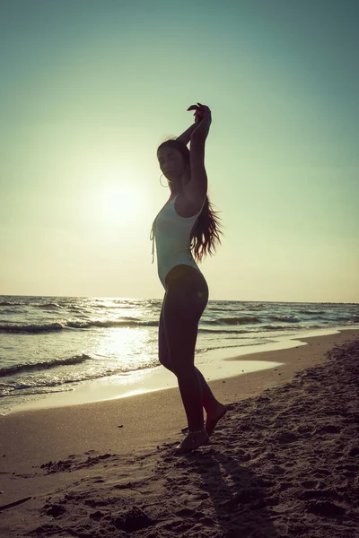 在一个阳光明媚的日子里 一个漂亮的年轻女子穿着海衣在海边的沙滩上摆姿势拍照 — 图库照片