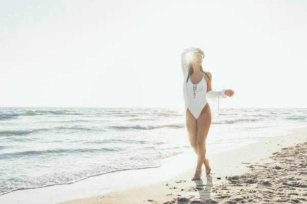 晴れた日の休日のために海の近くの砂に完全な白いドレス 海の衣装とシャツ を着ている美しい若い女性の写真撮影 ストック写真