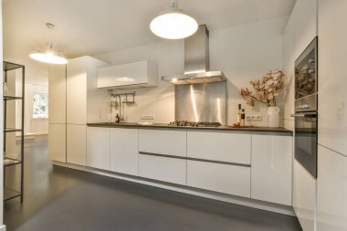 Stüdyo dairesinin modern minimalist tarzı iç tasarımı açık beyaz mutfak ve yemek masası ve sandalyeleri tavan arası lambasıyla aydınlatılmış.