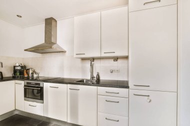 Minimalist tarzı beyaz mobilyalı, lavabolu ve sobalı bir ev mutfağı.