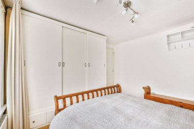 Yatak odasının iç tasarımı, yatak odası ve ahşap gardırop modern dairenin penceresinin kenarına yerleştirilmiş.