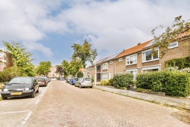 Arabaları, ağaçları ve fenerleri olan boş bir kaldırımdan panorama manzaralı evler.