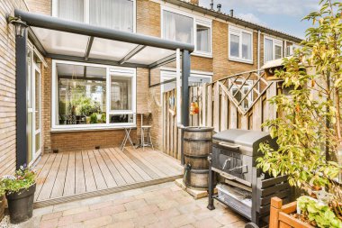 Oturma alanı ve ahşap çitlerin yanındaki küçük bahçesi olan düzgün asfaltlı bir avlu.