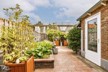 Oturma alanı ve ahşap çitlerin yanındaki küçük bahçesi olan düzgün asfaltlı bir avlu.