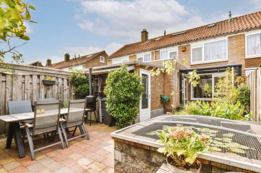 Oturma alanı ve ahşap çitlerin yanındaki küçük bahçesi olan düzgün asfaltlı bir avlu.