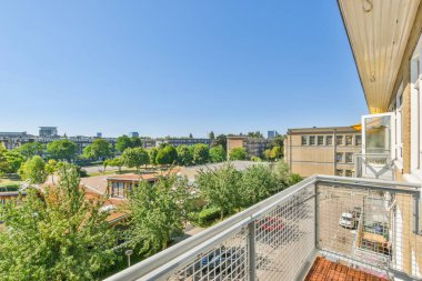 Panoramic view of brick buildings with parking and trees from small balcony