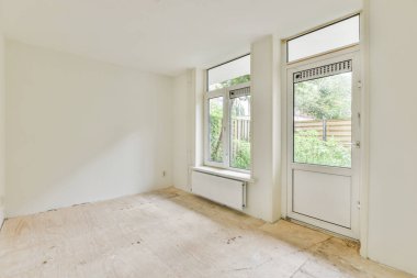 Evdeki boş ışık odasında, beyaz duvardaki plastik pencere ve radyatör.