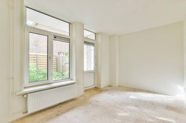 Evdeki boş ışık odasında, beyaz duvardaki plastik pencere ve radyatör.