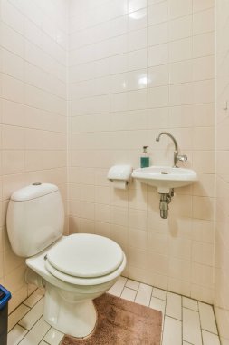 Evdeki modern tuvalette asılı duran banyo musluğu ile duvar arasındaki cam bölme.