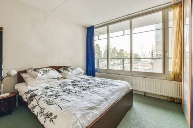 Yatak odası, yatak odası ve büyük pencerelere karşı klasik koltuk.