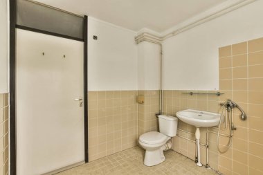 Tuvaletin sifonu küçük fayanslı banyoda lavabonun arasında.