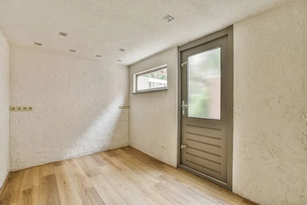 Interior of empty modern apartment with entrance door and white walls and parquet floor illuminated with lamp
