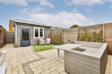 Neat paved patio with sitting area and small garden near wooden fence