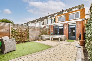 Oturma alanı ve ahşap çitlerin yanındaki küçük bahçesi olan düzgün asfaltlı bir avlu.