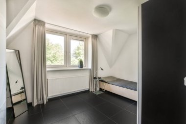 Beyaz duvarları, yumuşak rahat yatağı ve aydınlatmalı minimalist tarzı rafları olan küçük Mansard yatak odasının modern iç tasarımı.
