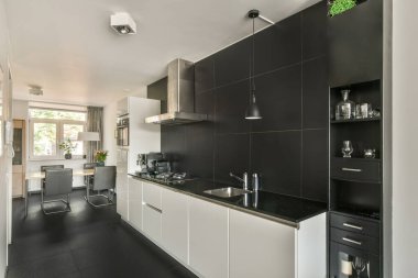 Çağdaş dairenin geniş odasındaki dinlenme odası ve mutfağın yakınındaki sandalyeli ve çiçekli masa.