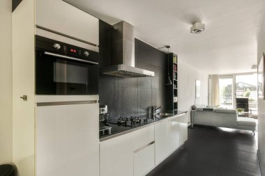 Çağdaş dairenin geniş odasındaki dinlenme odası ve mutfağın yakınındaki sandalyeli ve çiçekli masa.