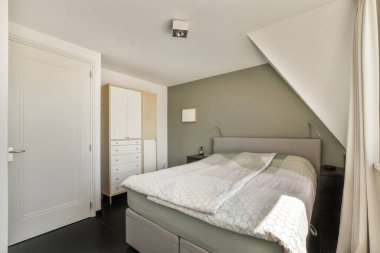 Beyaz duvarları, yumuşak rahat yatağı ve aydınlatmalı minimalist tarzı rafları olan küçük Mansard yatak odasının modern iç tasarımı.