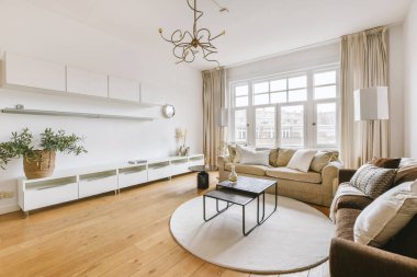 Yumuşak yastıklı rahat bir kanepe şık bir avizenin altında kemerli, ferah bir oturma odasında.