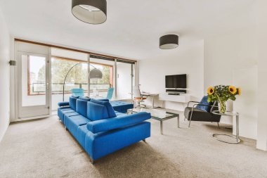 Çağdaş dairenin pencerelerine karşı rahat kanepesi ve televizyonu olan oturma odası.