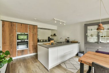 Çağdaş dairenin geniş odasındaki dinlenme odası ve mutfağın yakınındaki sandalyeli ve çiçekli masa.