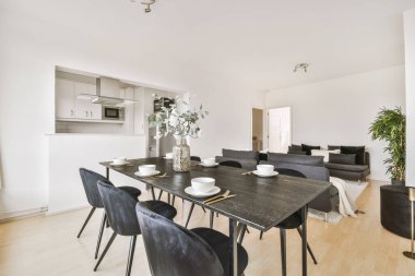 Günümüz minimalist tasarımı. Hafif stüdyo dairesinin ahşap masası ve oturma odası ile beyaz duvarları ve parke zemini arasında yemek masası ve sandalyeleri var.